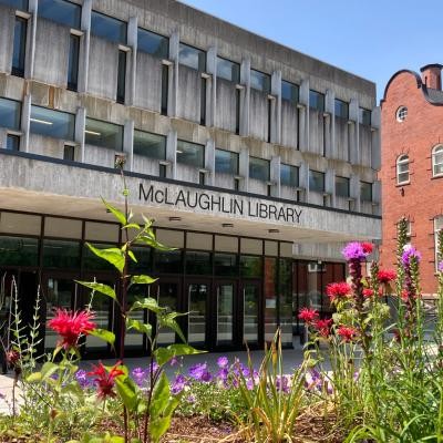 Exterior image of the McLaughlin Library with flowers blooming in the summer.