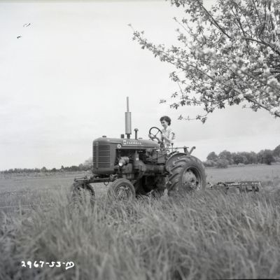 A woman farmer riding a tractor across a field.